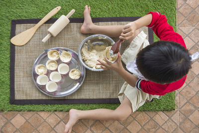 High angle view of boy filling batter in bowls