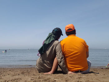 Rear view of men sitting on beach