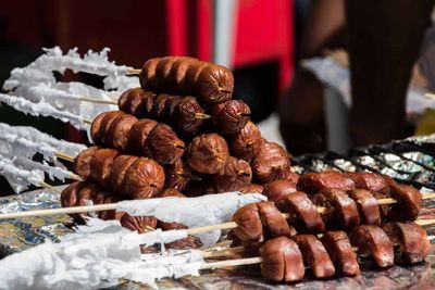 Stack of sausage on skewers next to outdoor grill