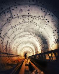 Rear view of person standing in illuminated tunnel