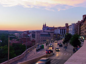 Vehicles on road against sky at sunset