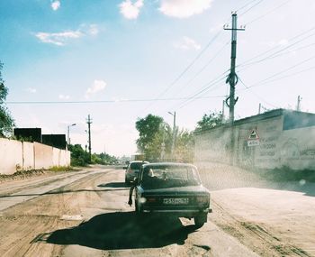 Vehicles on road against sky in city