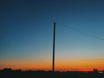 Low angle view of silhouette electricity pylon against sky during sunset