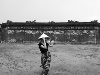 Portrait of woman in asian style conical hat standing on footpath