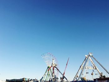 Low angle view of unfinished luna park against clear blue sky