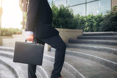 Low section of businessman with briefcase walking on steps