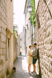 Woman standing on alley amidst buildings