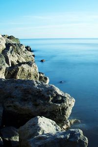 Scenic view of rocks by sea against sky