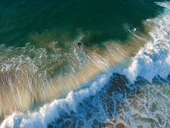 Drone view of beautiful turquiose sea waves breaking on sandy coastline. aerial shot 