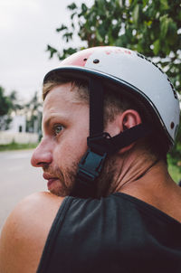 Close-up rear view of man wearing bicycle helmet while looking away on street