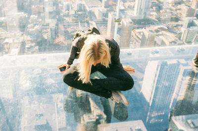 High angle view of woman sitting on glass at skydeck chicago in willis tower