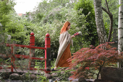 Happy ginger hair woman waling in well-groomed park or garden with fruits. freedom and healthy way