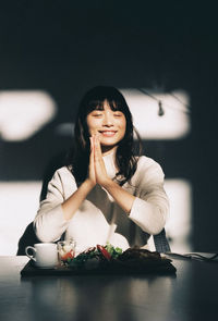 Portrait of a smiling young woman sitting on table