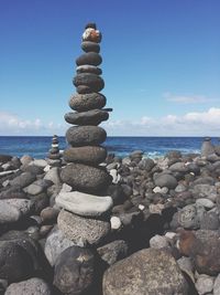 Stack of pebbles on beach against sky