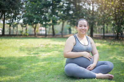 Portrait of pregnant woman smiling while sitting at park