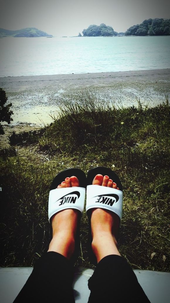 human leg, personal perspective, shoe, low section, one person, water, nature, land, black, sea, lifestyles, leisure activity, standing, limb, day, sky, footwear, beach, human limb, outdoors, grass, adult, sandal, human foot, plant, light, white, women, high angle view, sunlight, relaxation