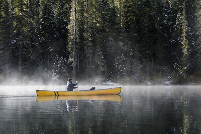 Man on boat in lake against trees in forest