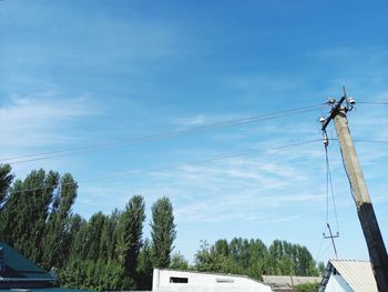 Low angle view of telephone pole by building against sky