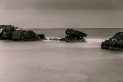 Scenic view of rocks in sea against sky