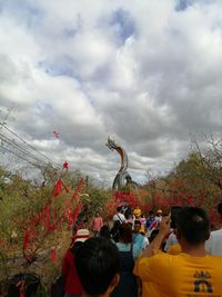 Rear view of people standing by plants against sky