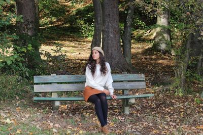 Portrait of young woman sitting on bench in park