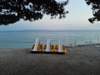 Deck chairs on beach against sky