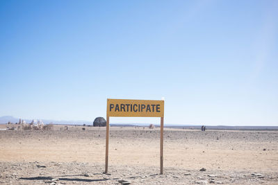 Participate information sign on desert against clear sky
