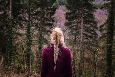 Full length of woman standing against trees in forest