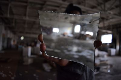 Person holding piece of mirror while standing in abandoned building