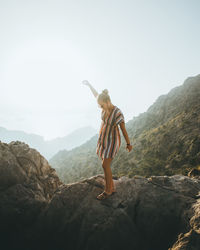 Full length of person standing on rock against sky