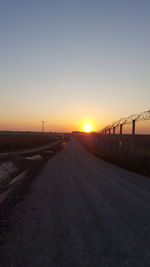 Empty country road against clear sky during sunset