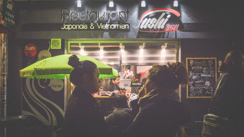Group of people standing in illuminated sign at night