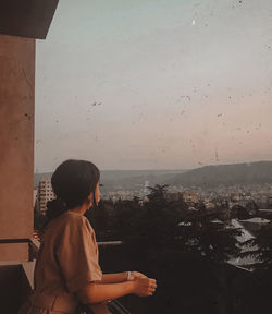 Rear view of man looking at cityscape against sky