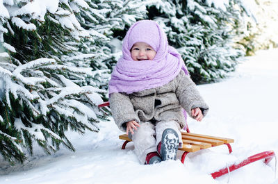 Portrait of smiling young woman sitting on snow