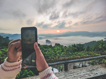 Midsection of man using mobile phone against sky