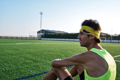 Young guy in sportswear sitting on the grass