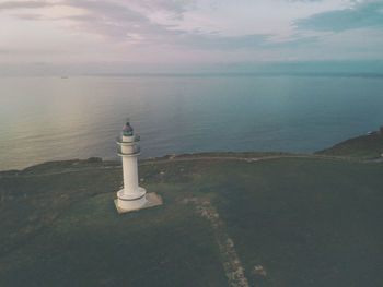 Lighthouse by sea against sky