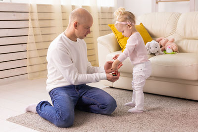 Young woman using phone while sitting on sofa at home