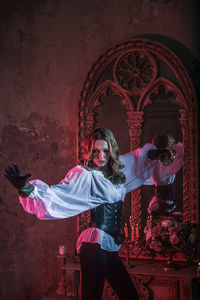 Portrait of woman in costume holding sword at abandoned building during night