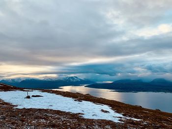 Scenic view of lake by snowcapped mountains against sky