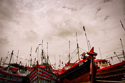 Low angle view of cranes at harbor against sky