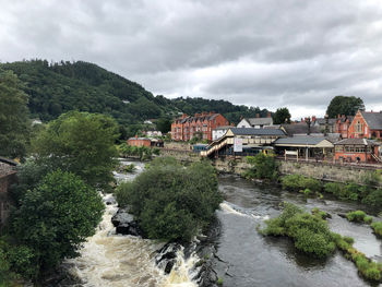 River amidst trees and houses against sky