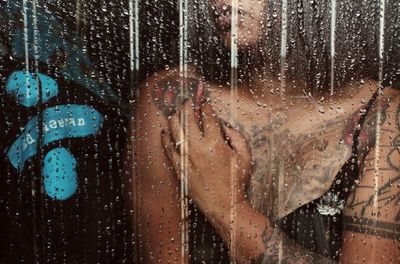 Young woman seen through wet window