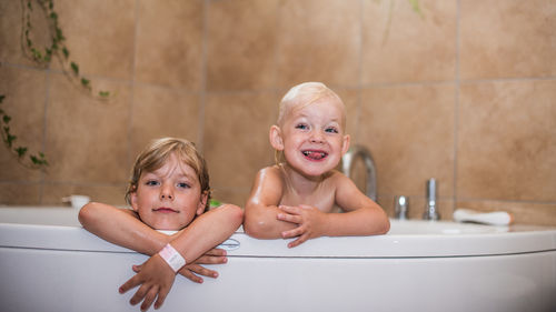 Happy sisters in bathtub at home