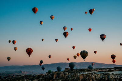 Hot air balloons flying over rocks against sky