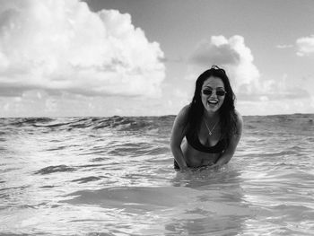 Portrait of woman laughing in sea against sky