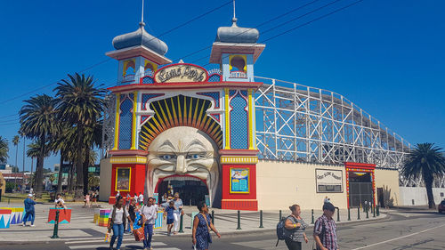 People at amusement park against blue sky