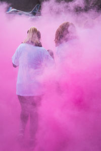 Rear view of woman standing against pink