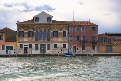 Buildings by canal against sky