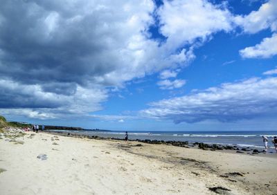 Scenic view of beach against cloudy sky